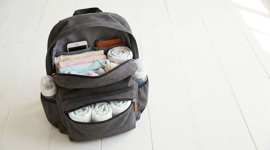 Top-down view of a perfectly organized open gray diaper bag backpack with neatly arranged diapers, bottles, clothes and parent essentials