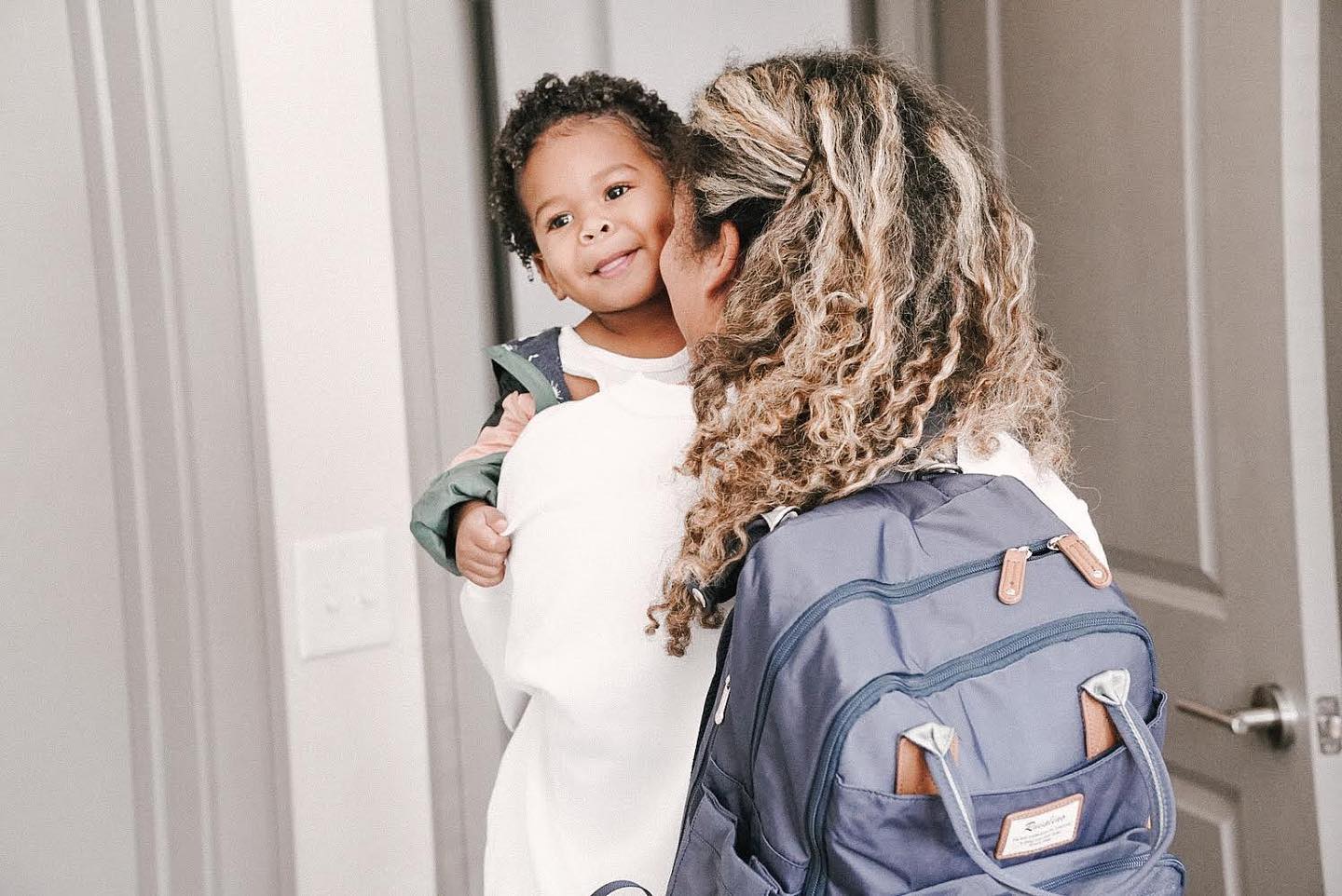 a mom wearing a purple backpack holding a baby 