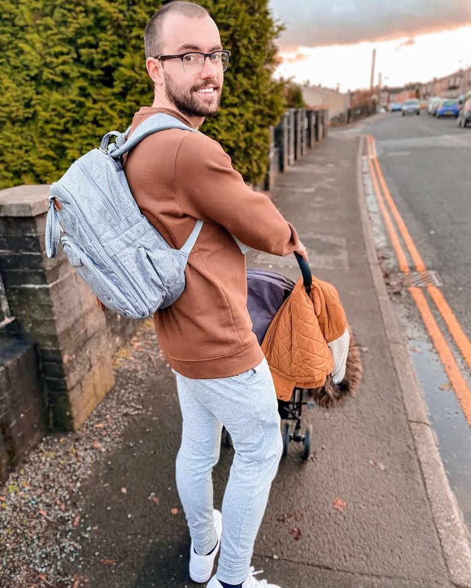 a smiling man looking back carrying a gray backpack