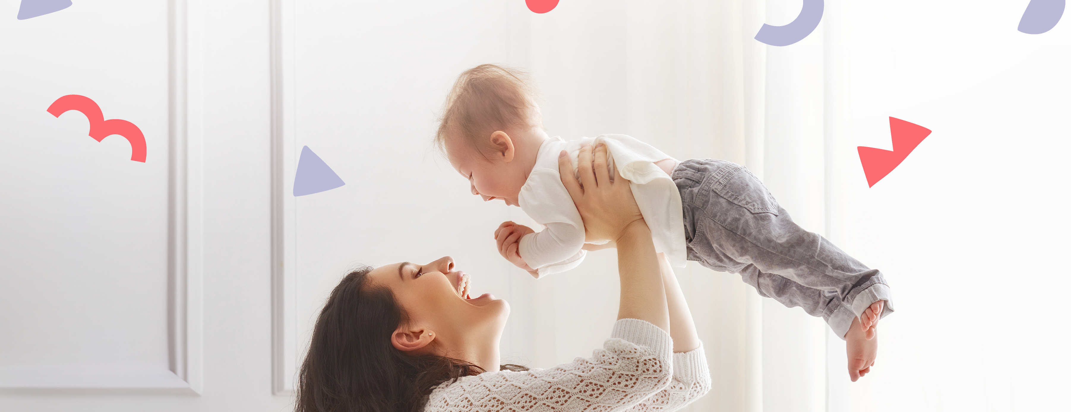 a happy mom picking up a happy baby with red and purple shapes floating in background 