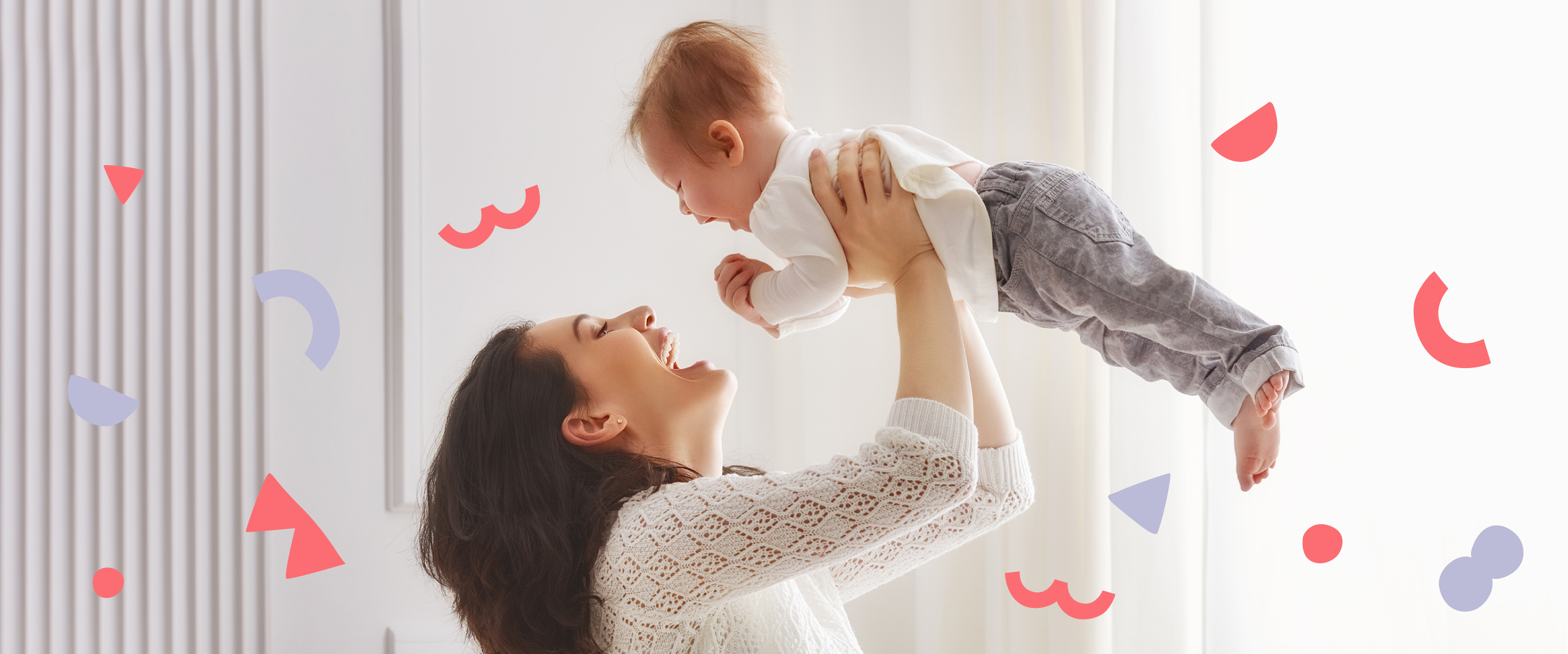 a happy mom picking up a happy baby with red and purple shapes floating in background 