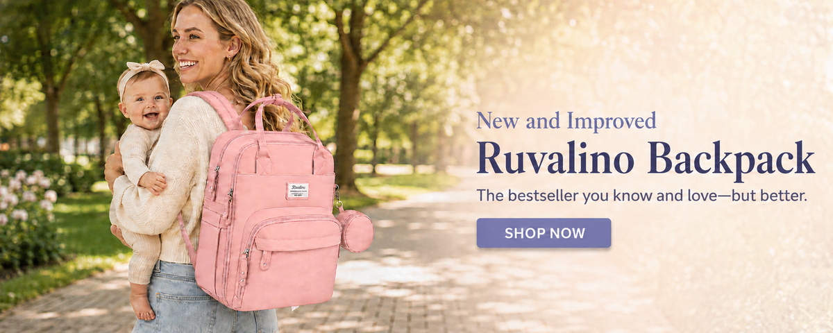 Smiling mother carrying her baby while wearing a pink Ruvalino diaper backpack in a sunny park